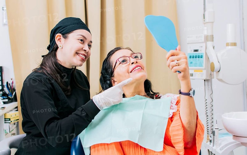 Satisfied female client in dental clinic looking at mirror