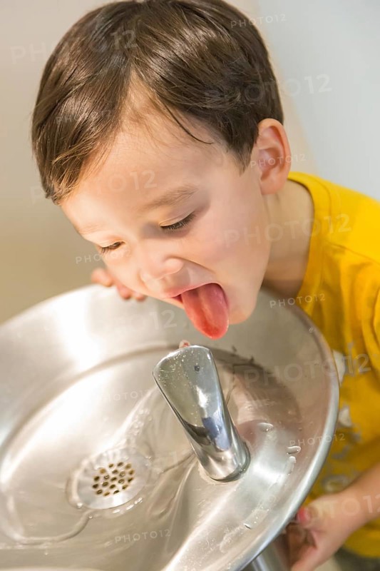 mixed-race boy drinking from the fresh water fountain