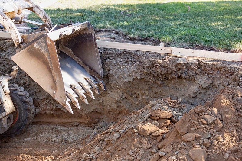 Small bulldozer digging in yard for pool installation