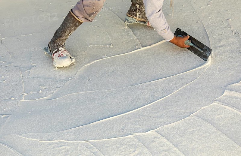 Worker wearing spiked shoes smoothing wet pool plaster with trowel