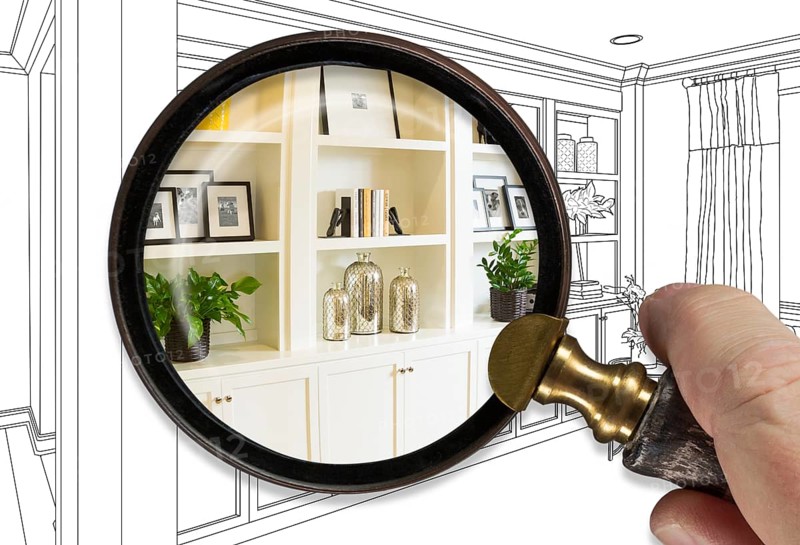 Hand holding magnifying glass revealing finished built-in over drawing