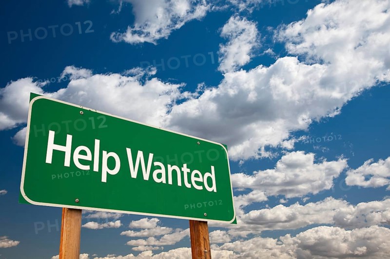 Help wanted green road sign with copy room over the dramatic clouds and sky