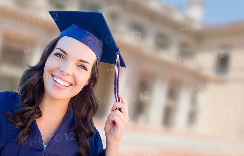 Happy graduating mixed-race woman in cap and gown celebrating on campus