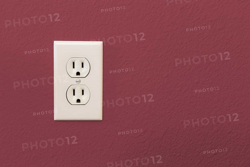 Electrical sockets in colorful burgundy wall of house