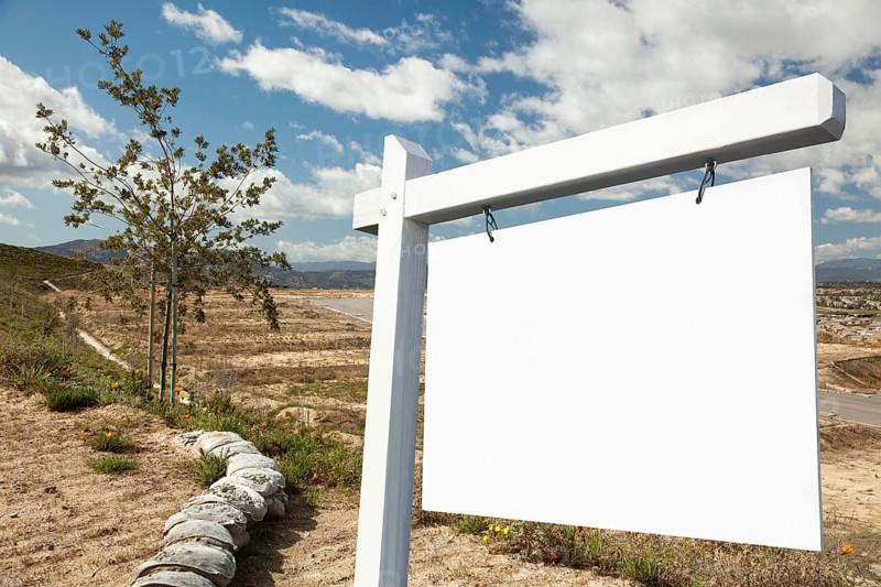 Blank real estate sign and empty construction lots