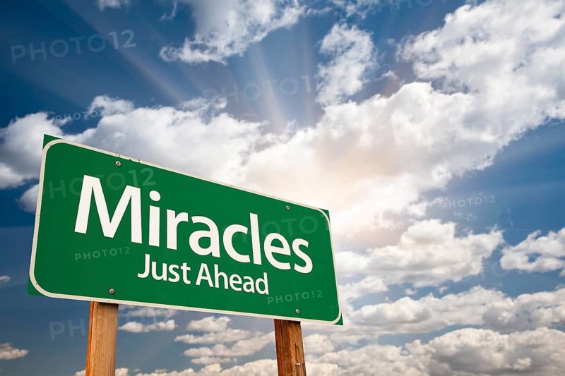 Miracles green road sign against clouds and sunburst