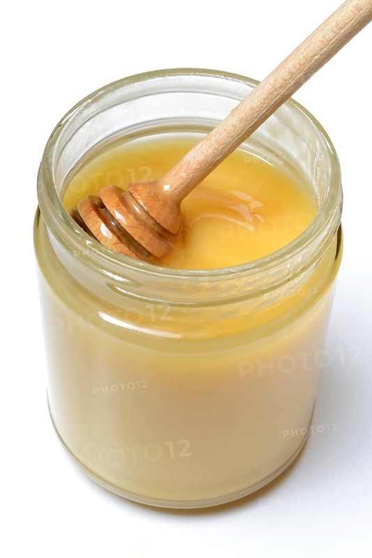 Cremiger Bienenhonig in Glas und Honigloeffel