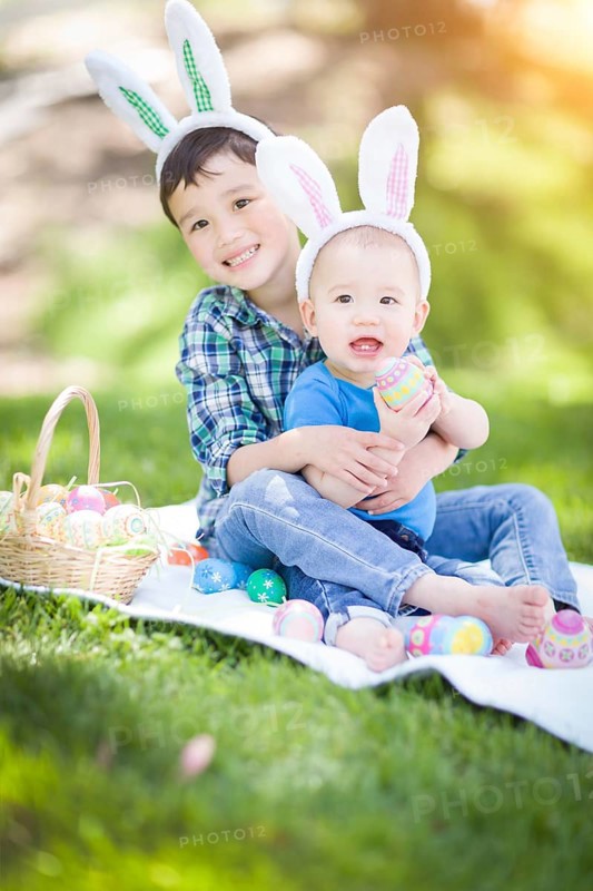 mixed-race chinese and caucasian boys outside in park playing with easter eggs