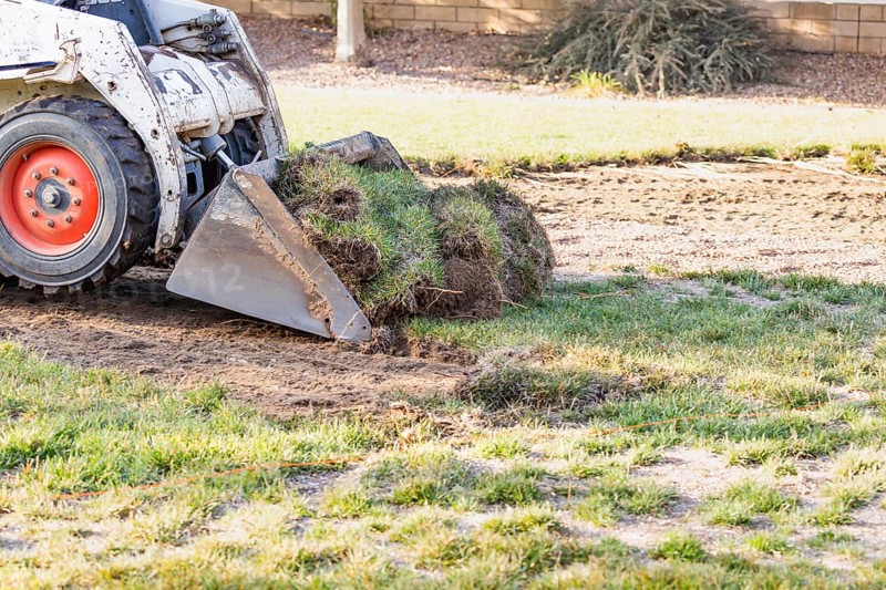 Small bulldozer removing grass from yard preparing for pool installation