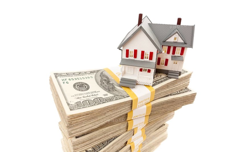 Small house on stacks of hundred dollar bills isolated on a white background