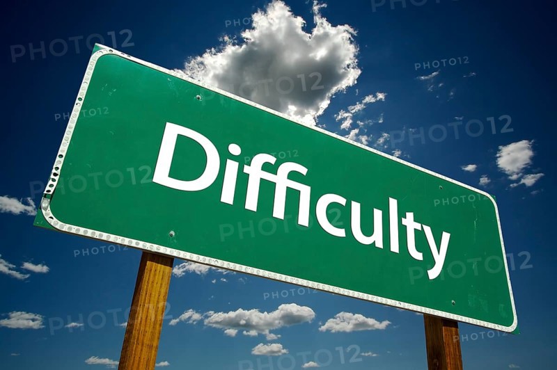 Difficulty road sign with dramatic clouds and sky