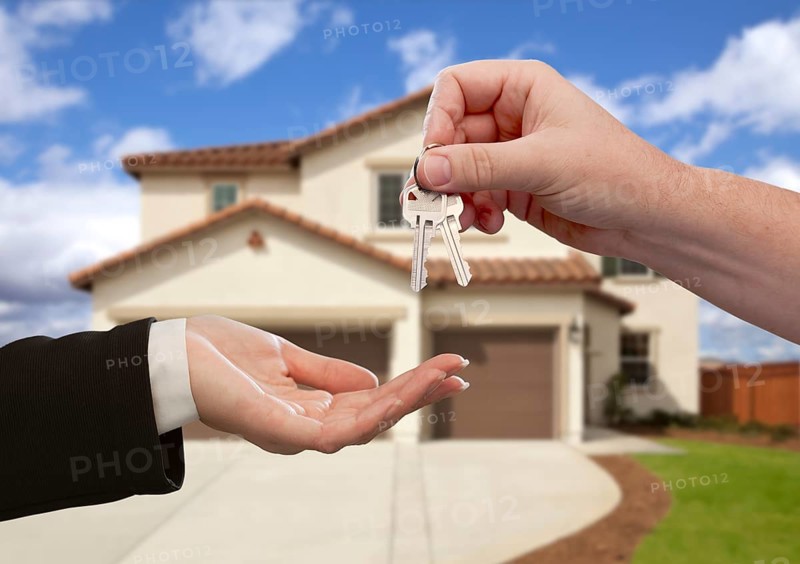 Handing over the house keys in front of a beautiful new home