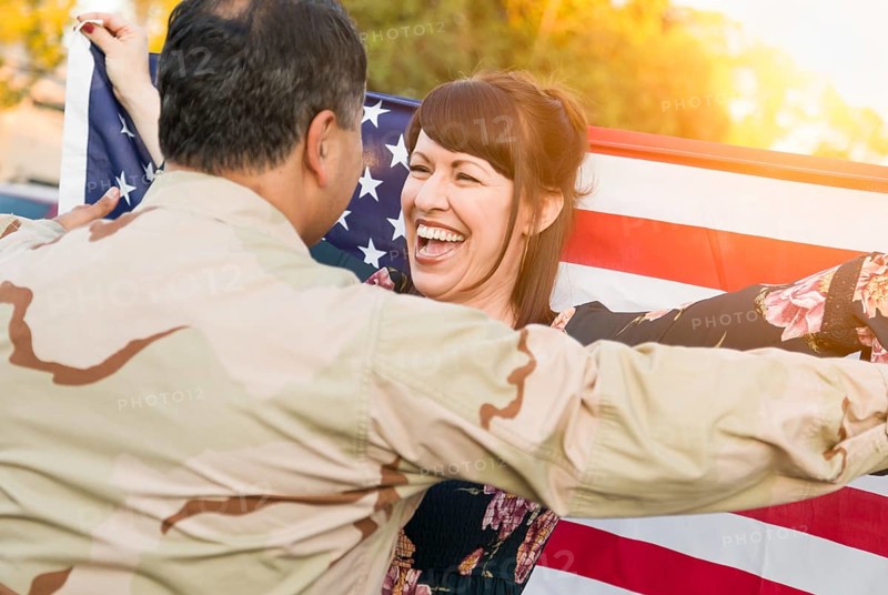 Excited woman with american flag runs to male military soldier returning home