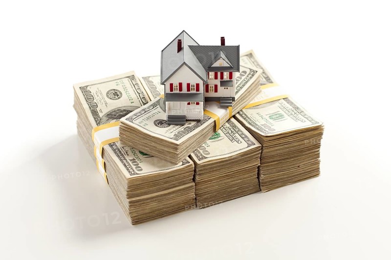 Small house on stacks of hundred dollar bills isolated on a white background