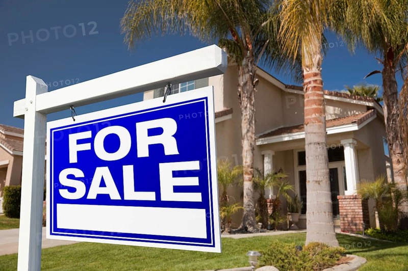 For sale real estate sign in front of house