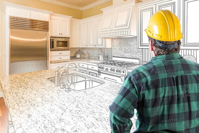 Male contractor with hard hat looking at custom kitchen drawing photo combination on white