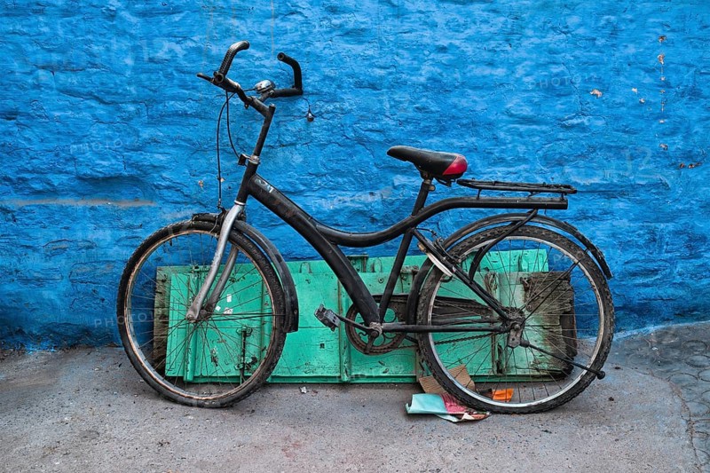 Old bicycle at the wall of blue house in streets of of Jodhpur