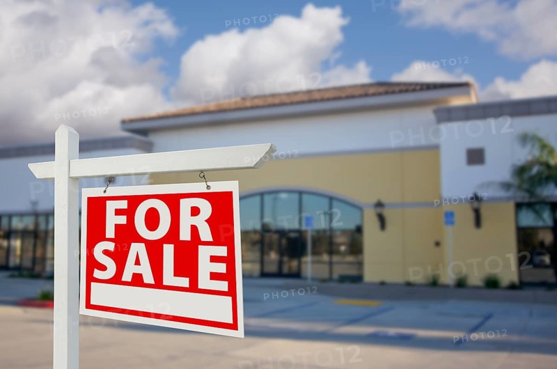 Vacant retail building with for sale real estate sign in front