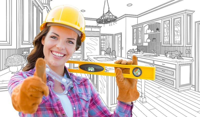 Female construction worker with thumbs up holding level in front of custom kitchen drawing