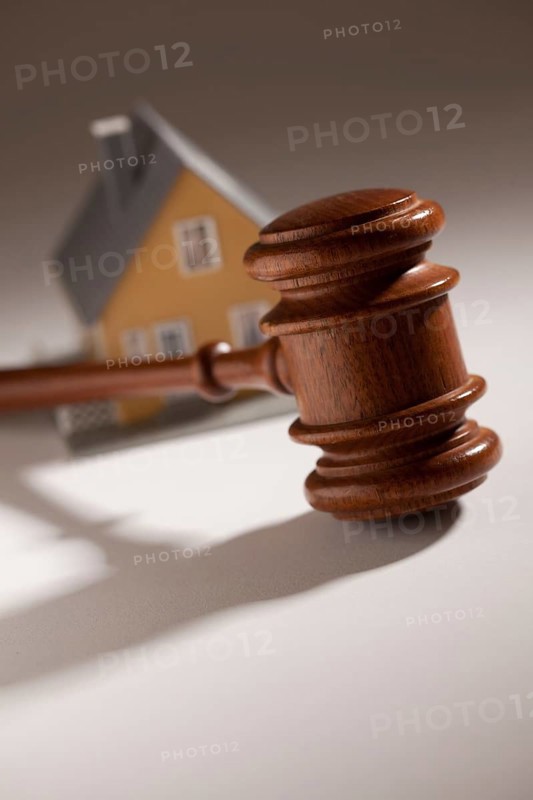 Gavel and model home on gradated background with selective focus