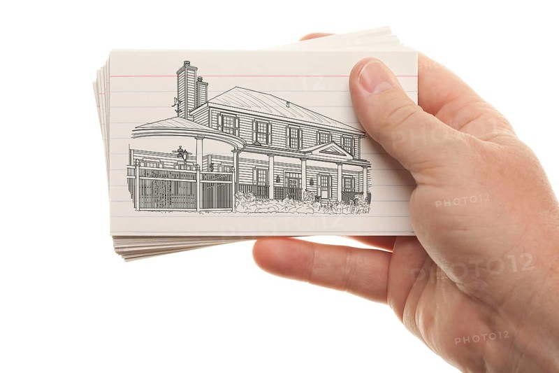 Male hand holding stack of flash cards with house drawing isolated on a white background
