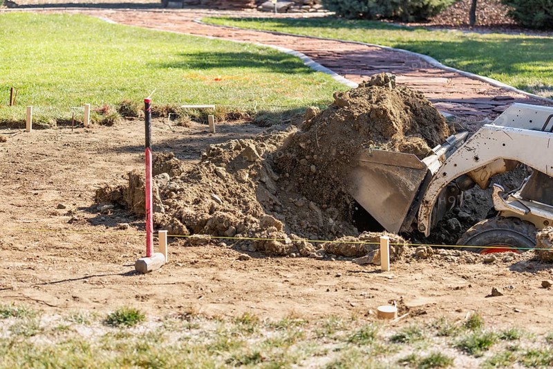 Small bulldozer digging in yard for pool installation