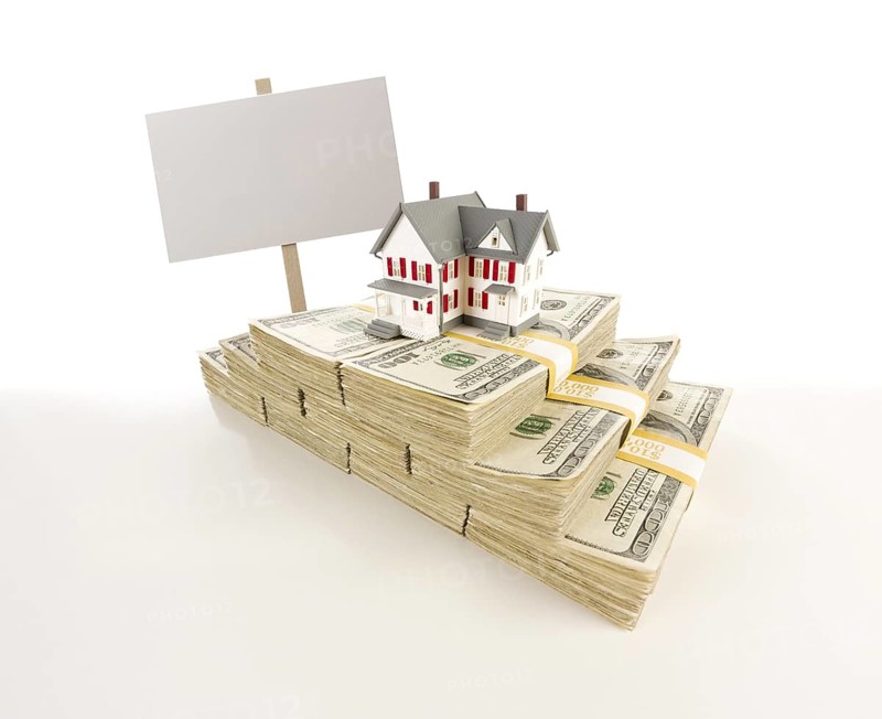Stacks of one hundred dollar bills with small house and blank sign on slight gradation