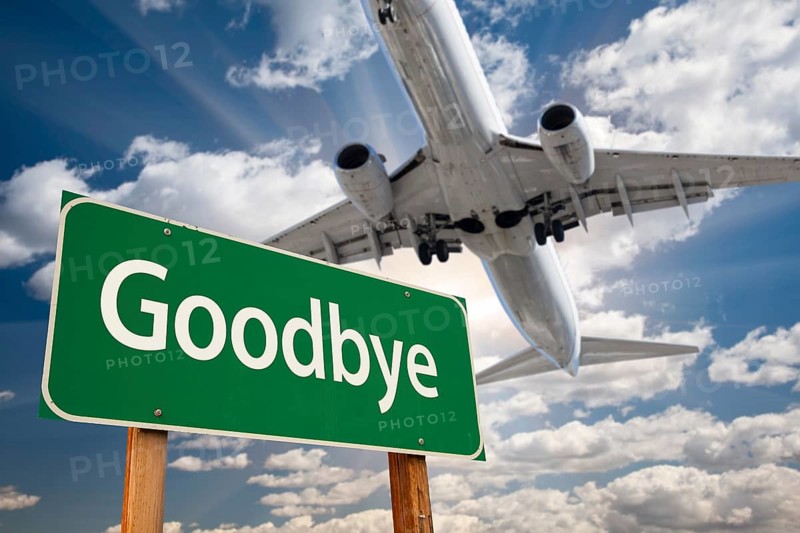 Goodbye green road sign and airplane above with dramatic blue sky and clouds