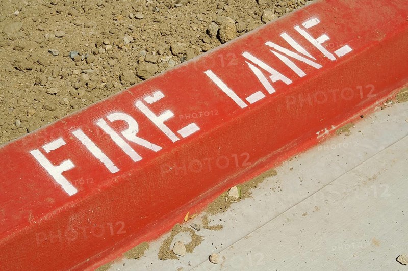 Close-up of red painted curb with fire lane text