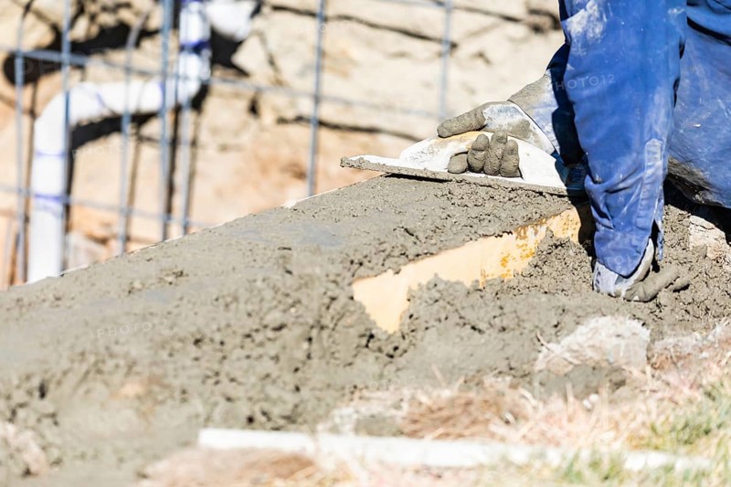 Pool construction worker working with wood float on wet concrete