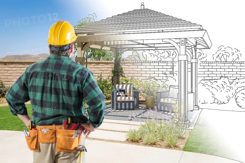 Contractor standing looking at patio pergola design drawing and photo combination