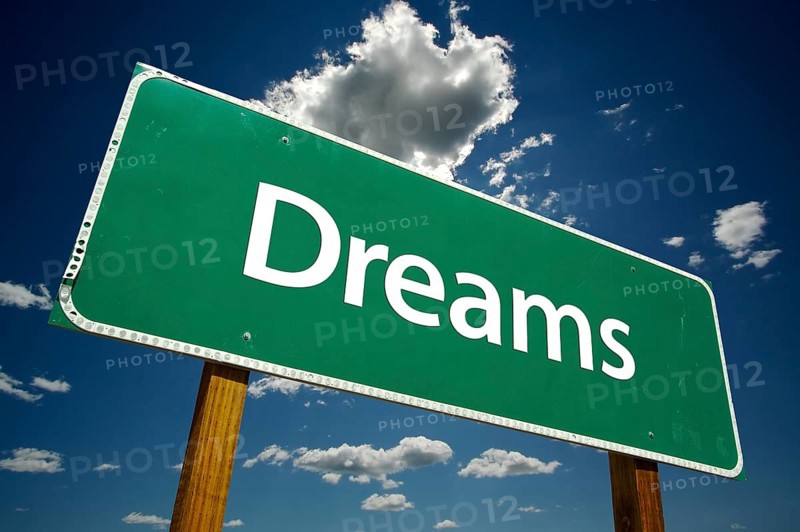 Dreams green road sign with dramatic clouds and sky