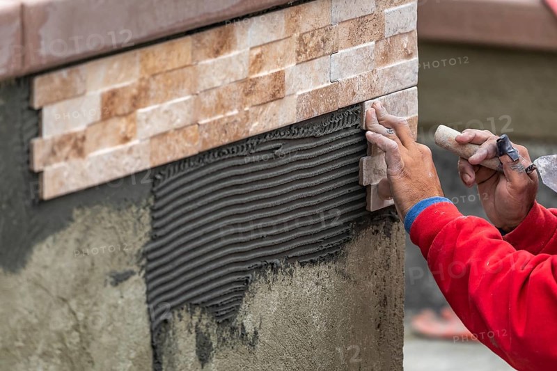 Worker installing wall tile at construction site