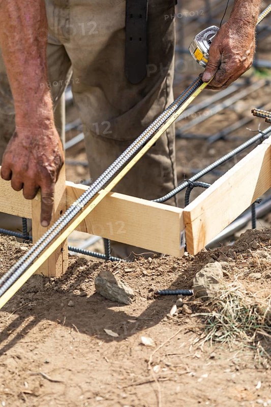 Worker measuring steel rebar at construction site