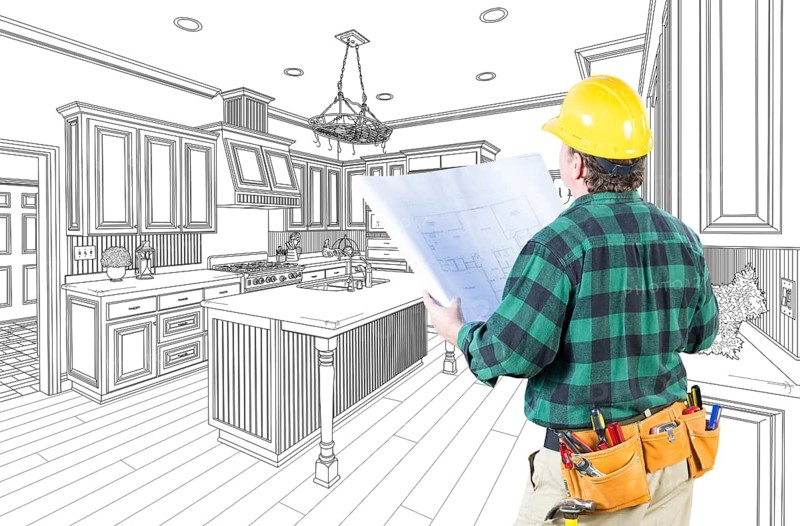Male contractor with hard hat and plans looking at custom kitchen drawing on white