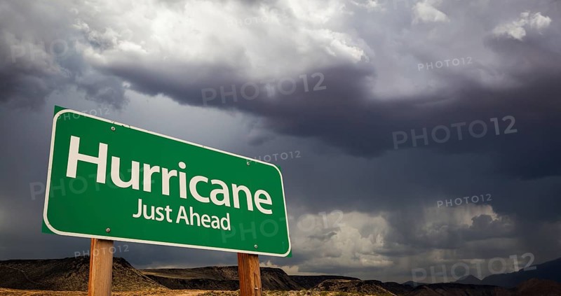 Hurricane just ahead green road sign with dramatic clouds and rain