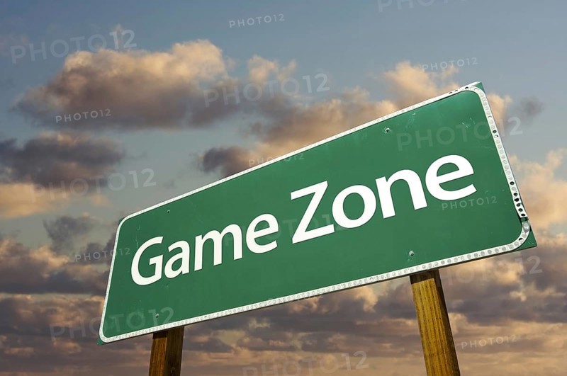 Game zone green road sign in front of dramatic clouds and sky