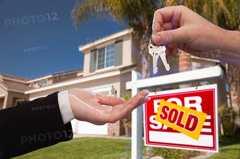 Handing over the house keys in front of a beautiful new home
