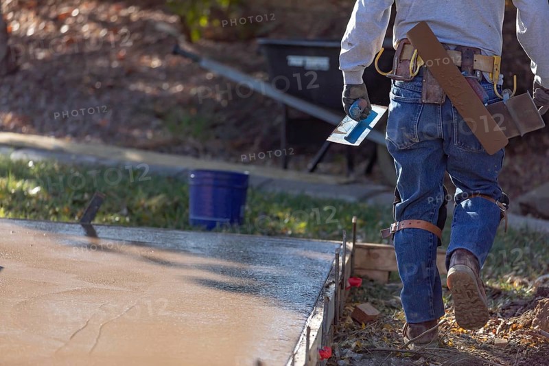 Construction worker with trowel tools near wet deck cement