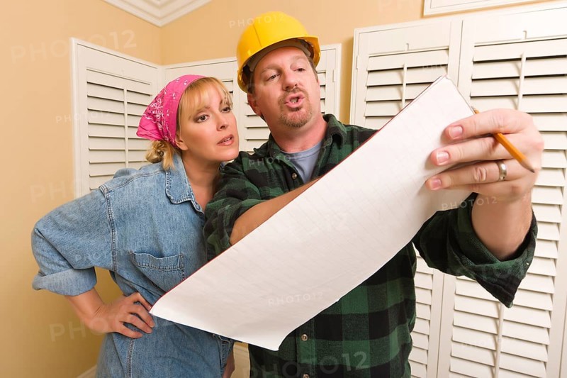Male contractor in hard hat discussing plans with woman in room