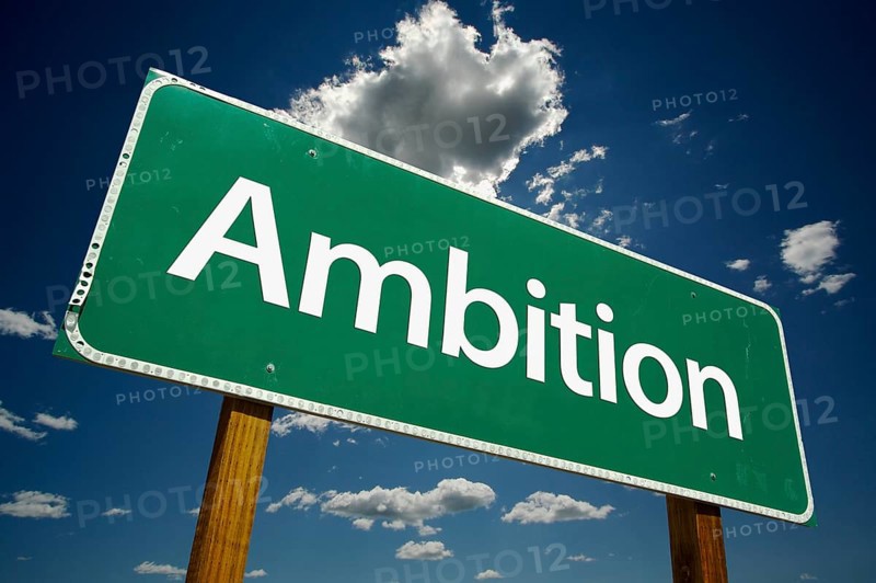Ambition green road sign over dramatic sky and clouds