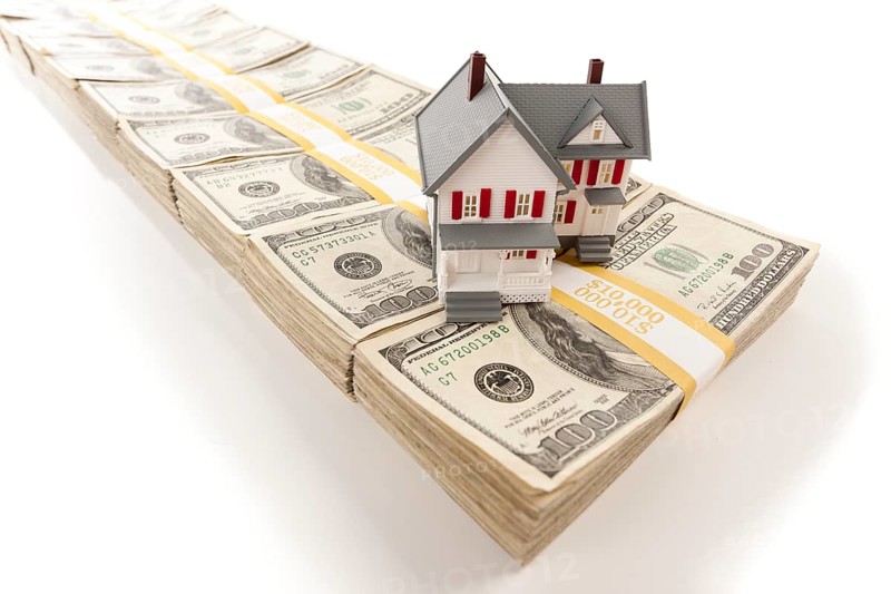 Small house on stacks of hundred dollar bills isolated on a white background