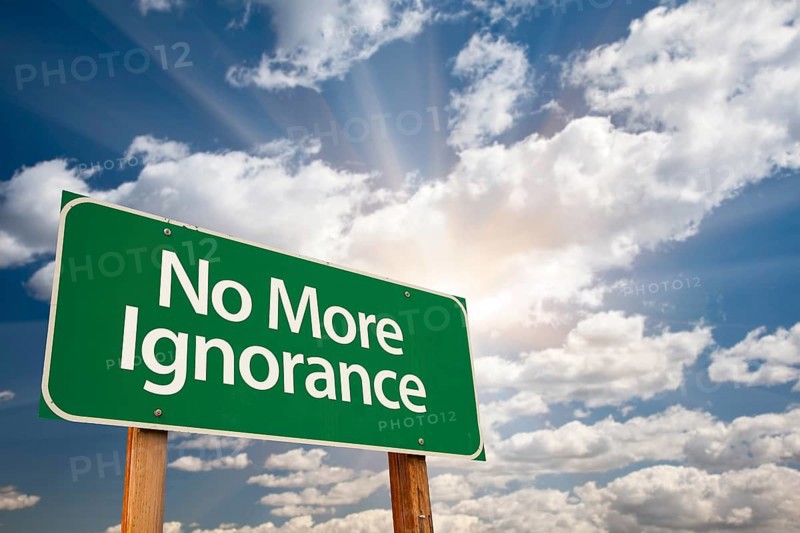 No more ignorance green road sign with dramatic clouds and sky