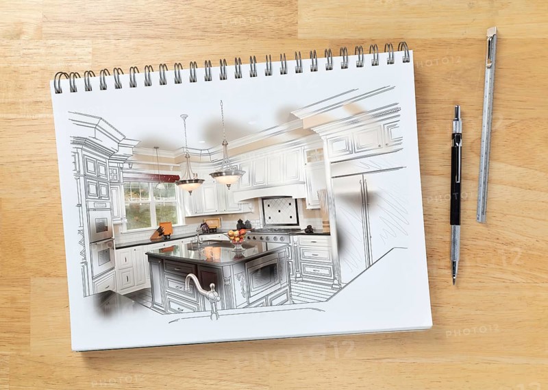 Sketch pad on desk with drawing of custom kitchen and brush stroke showing finished construction next to engineering pencil and ruler scale