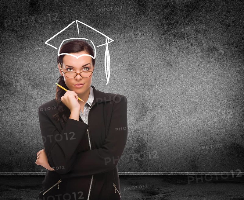 Graduation cap drawn on head of young adult woman with pencil in front of wall with copy space