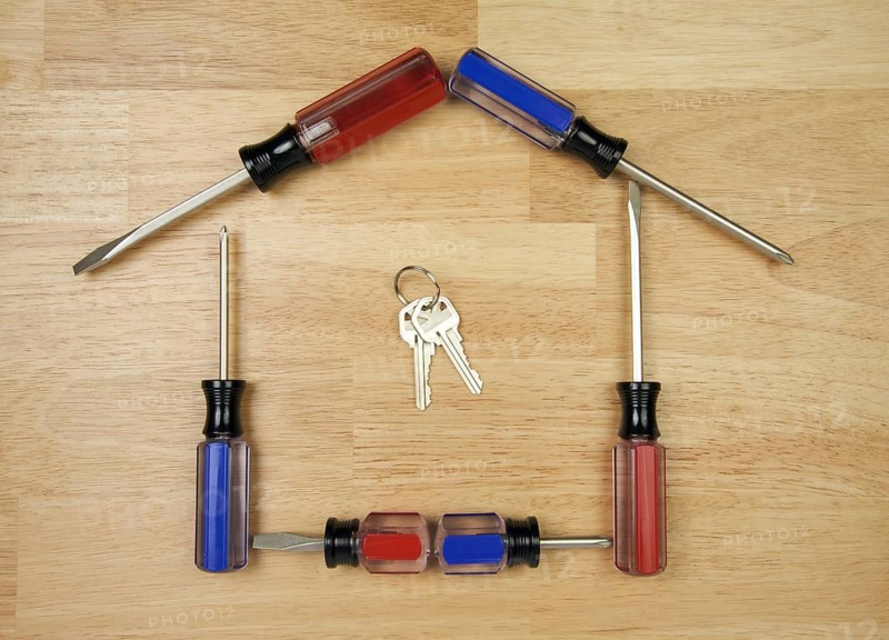 House shaped by screwdrivers and keys on a wood background