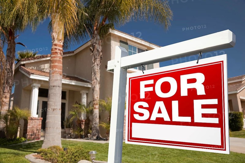 For sale real estate sign in front of house