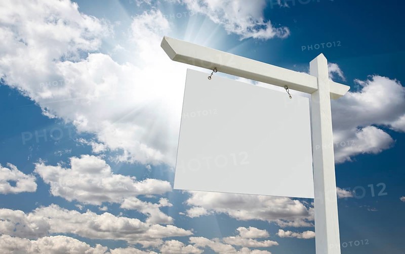 Blank real estate sign over clouds and blue sky with sun rays