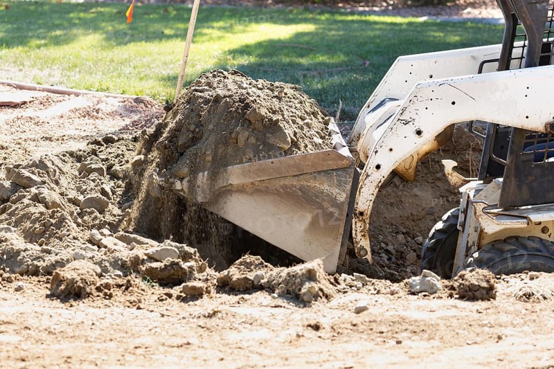 Small bulldozer digging in yard for pool installation