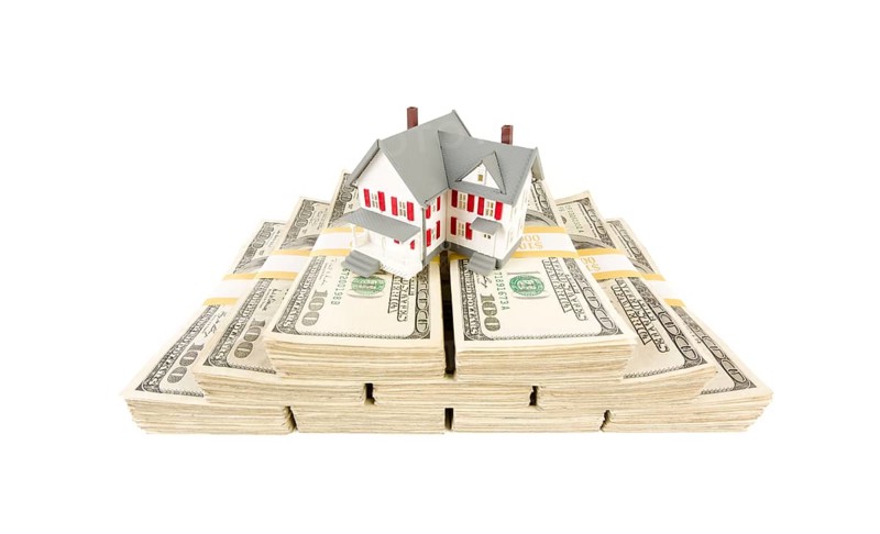 Small house on stacks of hundred dollar bills isolated on a white background